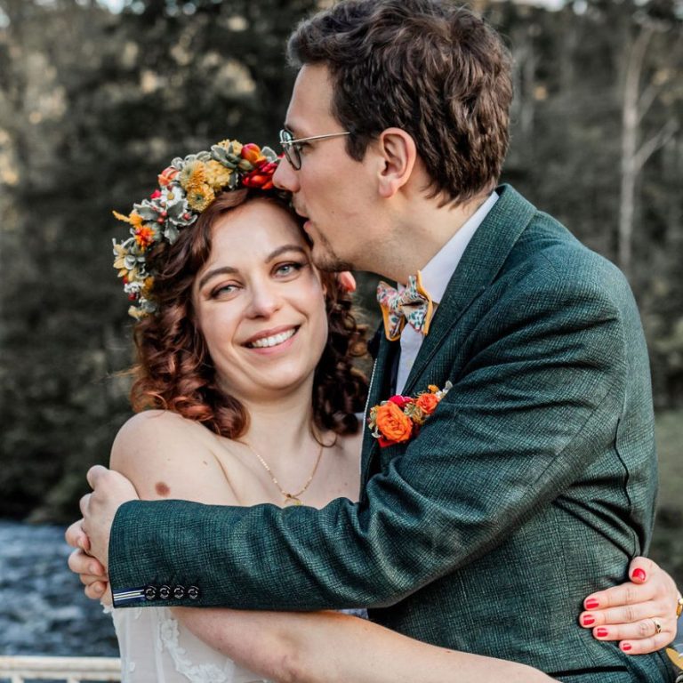 Femme à la tête rasée, regard pensif, avec un léger sourire et un fond flou.
