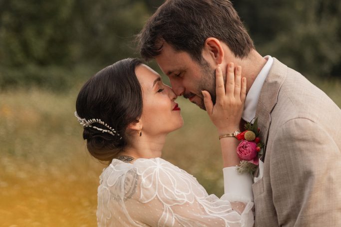 Un couple s'embrassant tendrement dans un champ, entouré de fleurs.